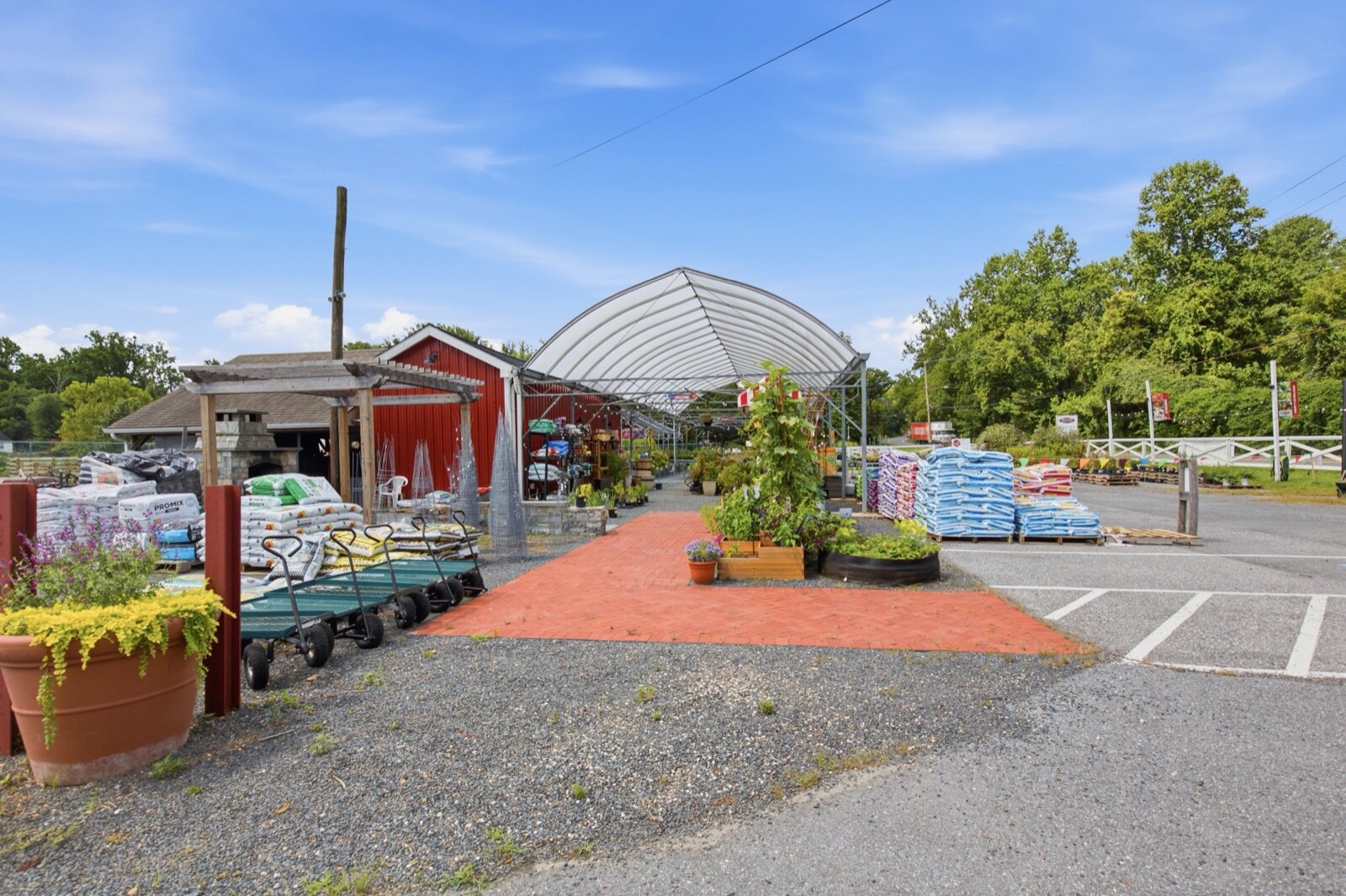 Pallets of bagged soil and mulch beside the hoop house and garden carts at Christopher's Garden Center