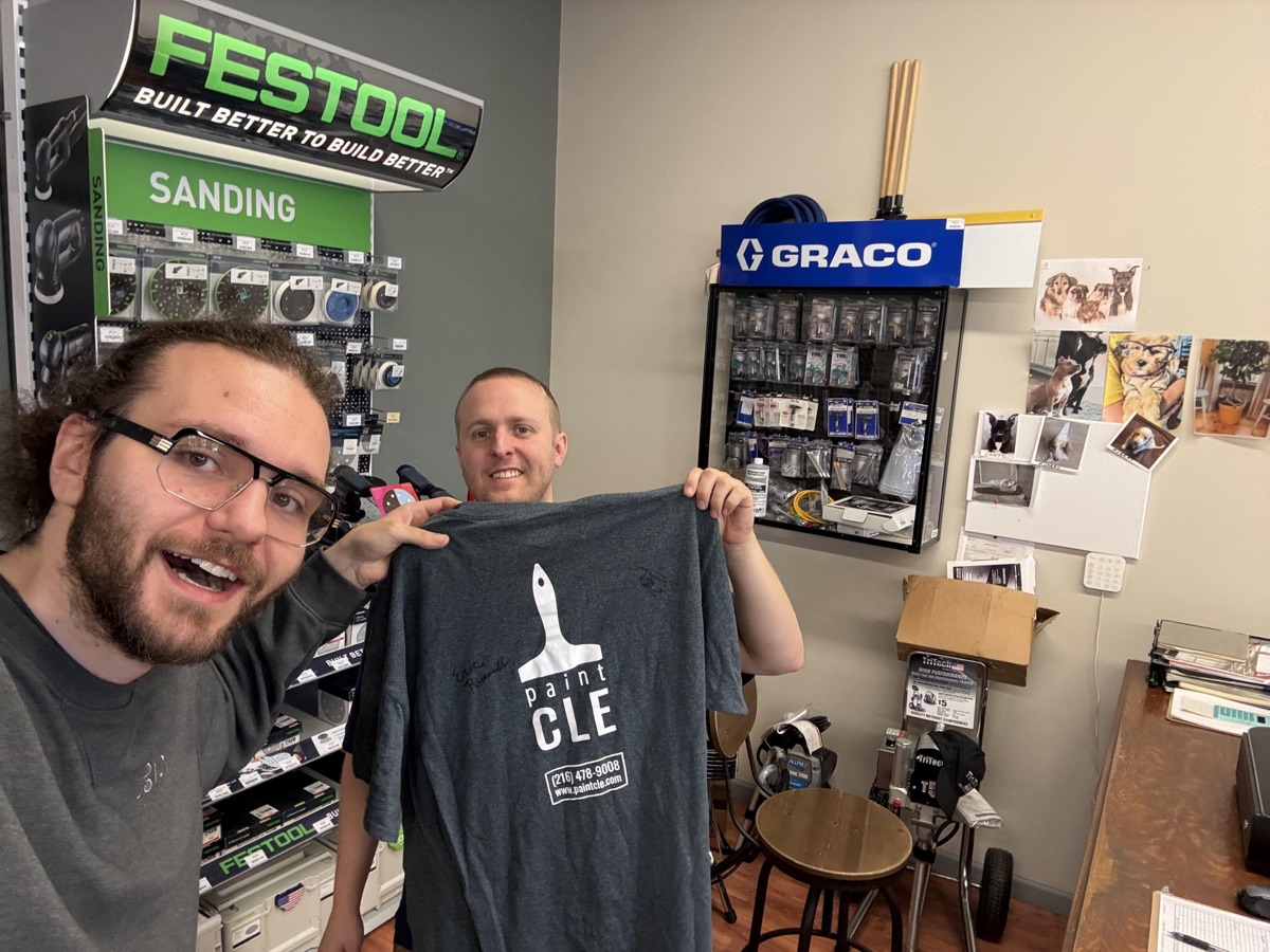 The paintCLE owner and a Rundoo team member holding their signed go-live shirt.