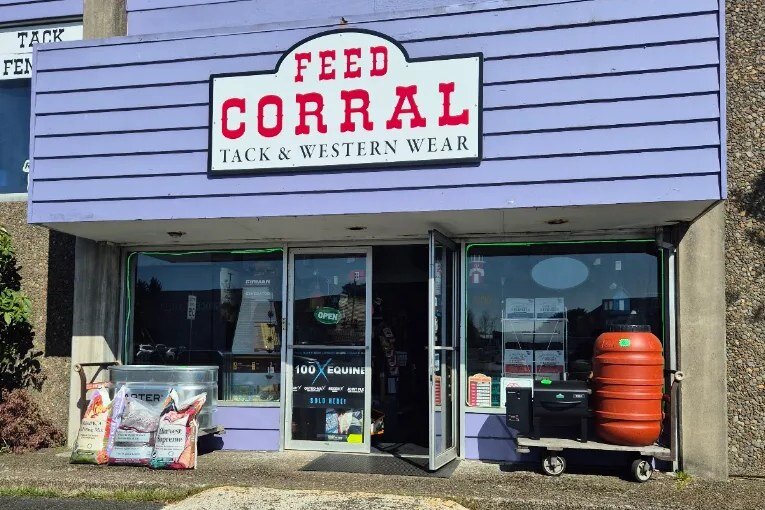 The Feed Corral Tack & Western Wear storefront, with bagged feed and a water barrel outside the windows.