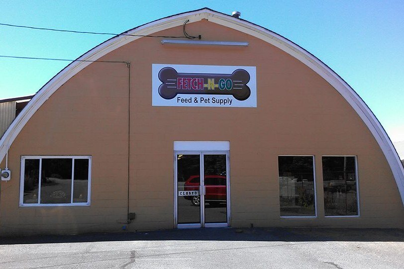 The arched Fetch N Go Feed & Pet Supply building with its bone-shaped sign over the front door.